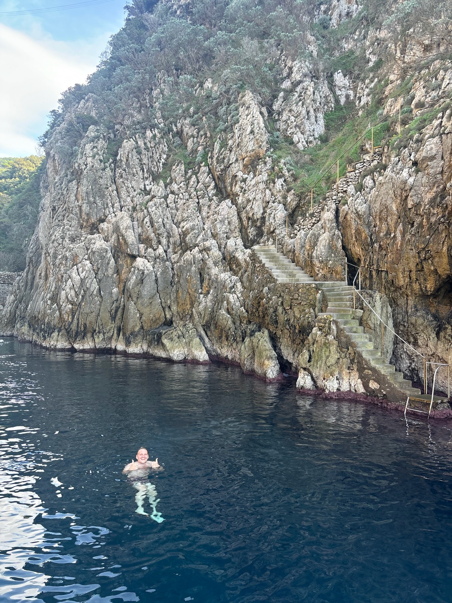 John Judge swimming near a rocky coastline